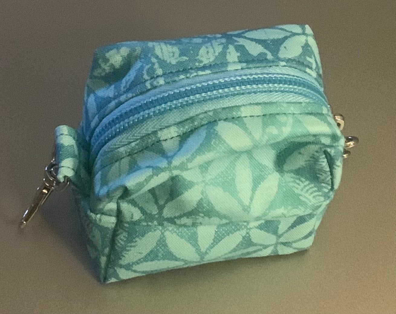 LW Designs poop bag holder with clip and compact design, shown in black fabric with metal clip attachment.