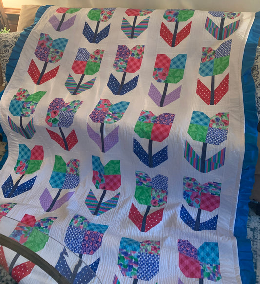 Twin size colorful tulip flower quilt by LW Designs with vibrant tulip patterns and soft fabric on a bed.