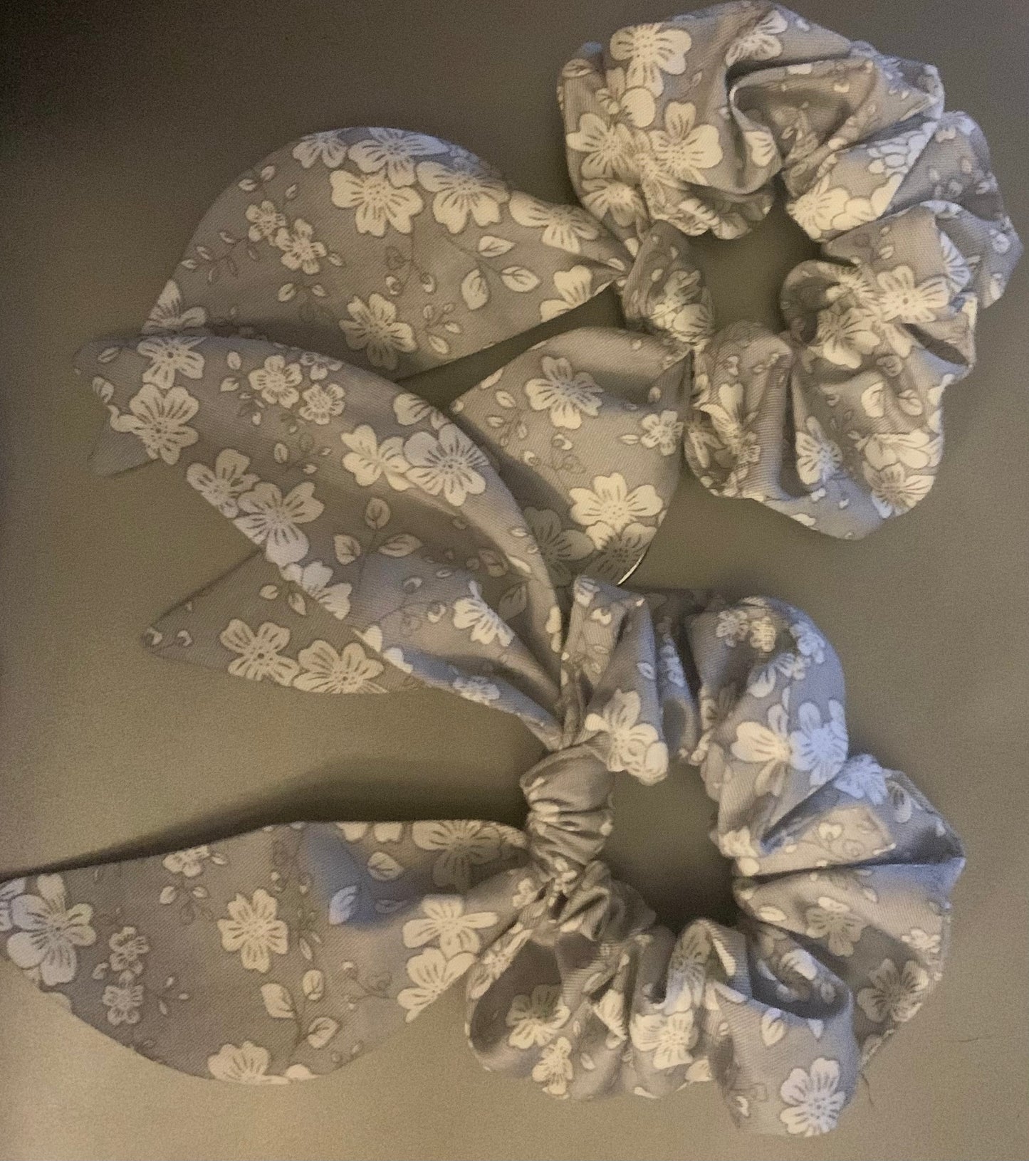 Light pink LW Designs hair scrunchies with soft fabric, arranged in a pile on a white background.