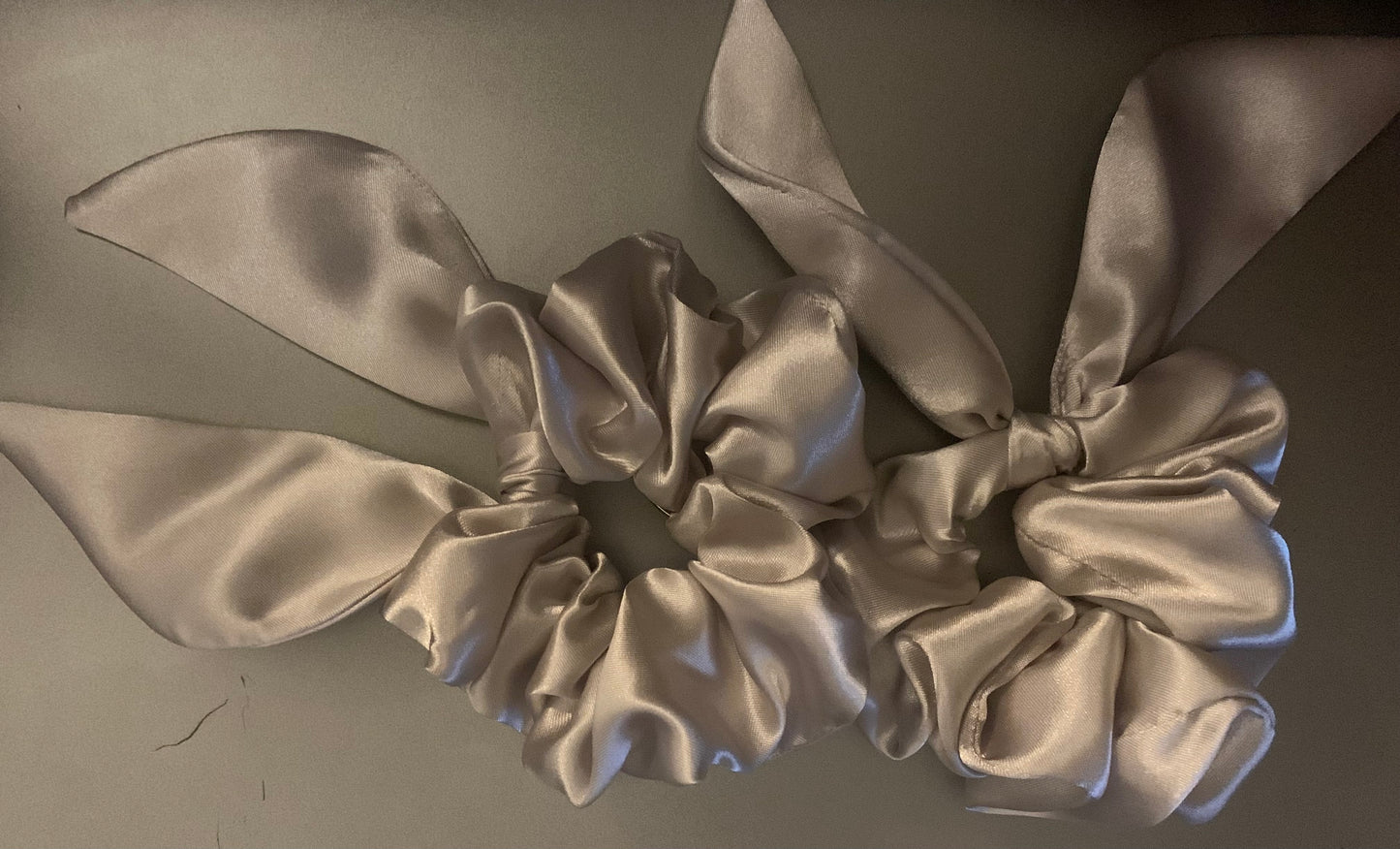 Cream-colored LW Designs hair scrunchies stacked together, soft fabric with elastic bands for gentle hold.