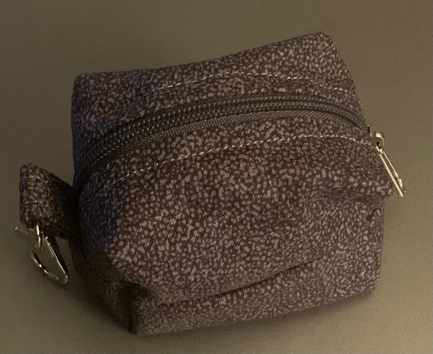 LW Designs poop bag holder with a compact, stylish design, featuring a clip and opening for easy access to waste bags.