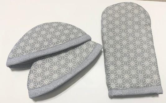 Pair of quilted pot holders from LW Designs with colorful, stitched patterns for heat protection in the kitchen.