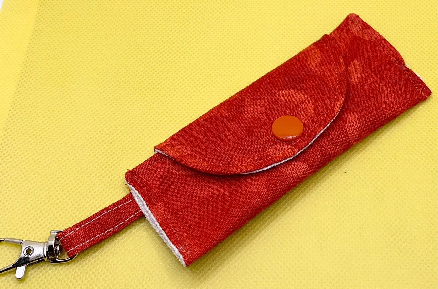 LW Designs lip balm holder with a colorful, woven design and a clip for easy attachment to bags or keychains.