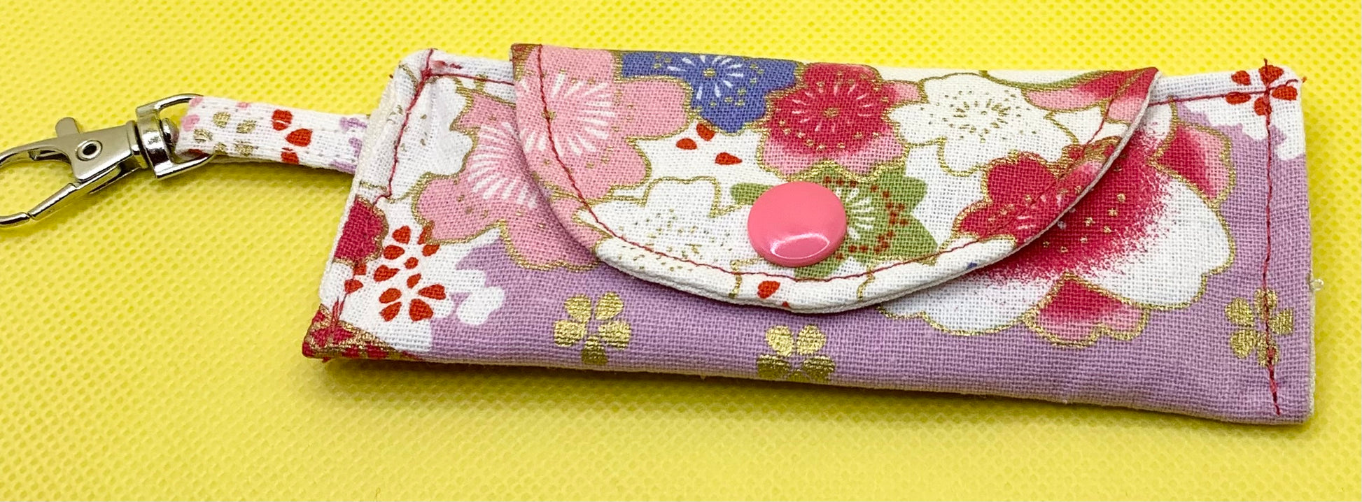 LW Designs lip balm holder featuring a colorful, compact design with a clip for easy attachment to bags or pockets.